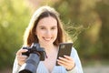 Photographer looks at you holding phone and camera