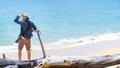 Photographer man standing on dead pine tree on the beach Royalty Free Stock Photo