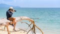 Photographer man taking photo on dead tree on the beach Royalty Free Stock Photo