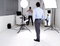Photographer, model and lighting with equipment in studio for career, behind the scenes or electronics. Photography Royalty Free Stock Photo
