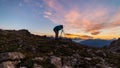 Photographer on mountain top with camera on tripod at sunrise light colorful sky scenis landscape, conquering success leader conce