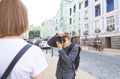 Photographer photographs a girl on the streets of the town. Model poses, photographer picks up Royalty Free Stock Photo
