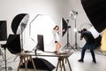 Photographer and pretty model working in modern lighting studio