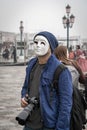 A photographer with a professional camera in mask with Venetian lamppost at background at St Mark\'s Square