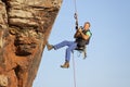 Photographer and rock climber taking pictures in while hanging in front of a rock