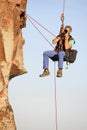 Photographer and rock climber taking pictures in while hanging in front of a rock