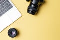 Photographer`s workplace on a yellow background. Modern laptop, digital camera, lens, battery, smartphone. Minimalism. Top view.