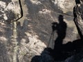 Photographer shadow wtih camera on tripod. Man silhouette on rocky wall