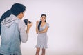 Photographer shooting with Asian model holding cosmetic products in her hand Royalty Free Stock Photo