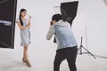 Photographer shooting with Asian model holding cosmetic products in her hand Royalty Free Stock Photo