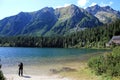 Photographer shoots landscape with mountains, lake and forest using tripod