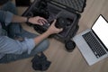 Photographer sitting on floor and putting camera accessories in special bag.