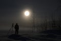 Photographer standing in snow in winter moonlight