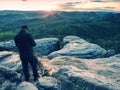 Photographer takes photos with camera on tripod on rock Royalty Free Stock Photo