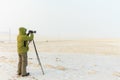 Photographer takes pictures with a tripod in winter, yellow landscapes of the island of Olkhon, Baikal, Russia