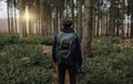 Person with backpack is holding a camera in his hand and is looking into the forest with beautiful view