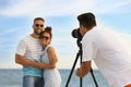 Photographer taking picture of couple with professional camera near sea Royalty Free Stock Photo