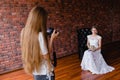 Photographer taking pictures the bride in the studio on a large leather armchair Royalty Free Stock Photo