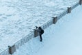 Photographer taking a pictures of a frozen lake from a shore railing after a cold winter night Royalty Free Stock Photo