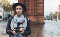 Photographer tourist hold retro photo camera. Young girl in hat travels in Triumphal arch Barcelona. Holiday concept street Royalty Free Stock Photo