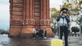 Photographer tourist make photo on retro camera. Girl in hat with suitcase travels in Triumphal arch Barcelona. Holiday concept Royalty Free Stock Photo