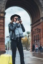 Photographer tourist with retro photo camera. Girl in hat travels in Triumphal arch Barcelona. Holiday concept street in europe Royalty Free Stock Photo