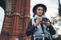 Photographer tourist with retro photo camera. Girl in hat travels in Triumphal arch Barcelona. Holiday concept street in europe Royalty Free Stock Photo