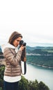 Photographer tourist traveler standing on green top on mountain holding in hands digital photo camera, hiker taking click photogra