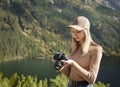 Photographer tourist traveler standing on green top on mountain holding in hands digital photo camera Royalty Free Stock Photo