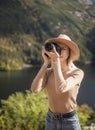 Photographer tourist traveler standing on green top on mountain holding in hands digital photo camera Royalty Free Stock Photo