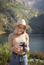 Photographer tourist traveler standing on green top on mountain holding in hands digital photo camera Royalty Free Stock Photo