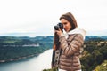 Photographer traveler on green top on mountain, tourist looking holding in hands digital photo camera, hiker taking click photo Royalty Free Stock Photo