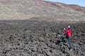 Photographer and traveller taking a picture of volcanic lava stones standing on clinker field near mountains