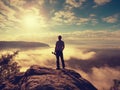 Photographer with tripod with camera in hands stand on rocky view point