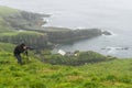 Photographer is waiting for the right shot on Mikines, Faroe Isl