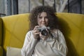 Curly haired photographer woman holding her camera in a cafe and shooting Royalty Free Stock Photo