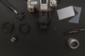 Photographer workplace with dslr camera system, camera cleaning kit, lens and camera accessory on dark black table background.