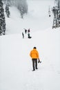 Photographer in a yellow jacket following a group of children having fun in a snowy wilderness