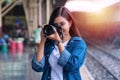 Woman taking pictures holding digital camera while standing in the train station. Attractive girl traveler with Royalty Free Stock Photo