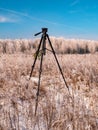 A photographers tripod against the backdrop of a winter landscape