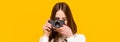Photographing girl make photography taking concept. Girl with a cameras. Woman holding camera over yellow background Royalty Free Stock Photo