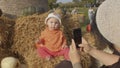 Photographing a small child using your phone. Portrait of a kid in the hay.