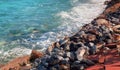 a photography of a beach with a red walkway and a blue ocean, breakwater along the shore of a beach with a red walkway