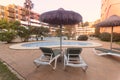 Photography of deck chair and umbrella and a pool, a residential area during the sunset with palms and pool