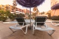 Photography of deck chair and umbrella and a pool, a residential area during the sunset with palms and pool