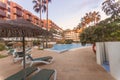 Photography of deck chair and umbrella and a pool, a residential area during the sunset with palms and pool