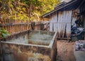 a photography of a dirty bathtub in a backyard with a wooden fence, vat in a dirty yard with a wooden fence and a trash can