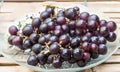 a photography of a glass bowl of grapes on a wooden table, grapes are on a glass plate on a wooden table