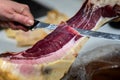 Iberian ham cut into small slices with a knife.