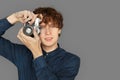 Photography Hobby. Teenager boy standing isolated on grey taking photo on camera thoughtful close-up